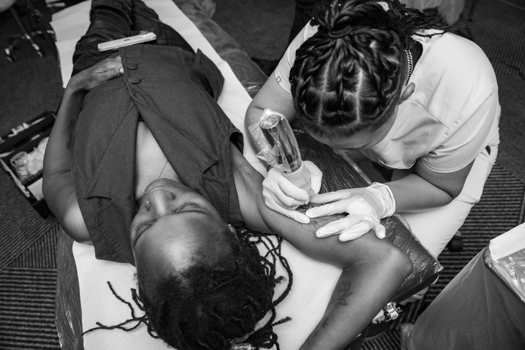Black and white overhead photograph of gloved hands working on a brow, Queen's Night 2026.